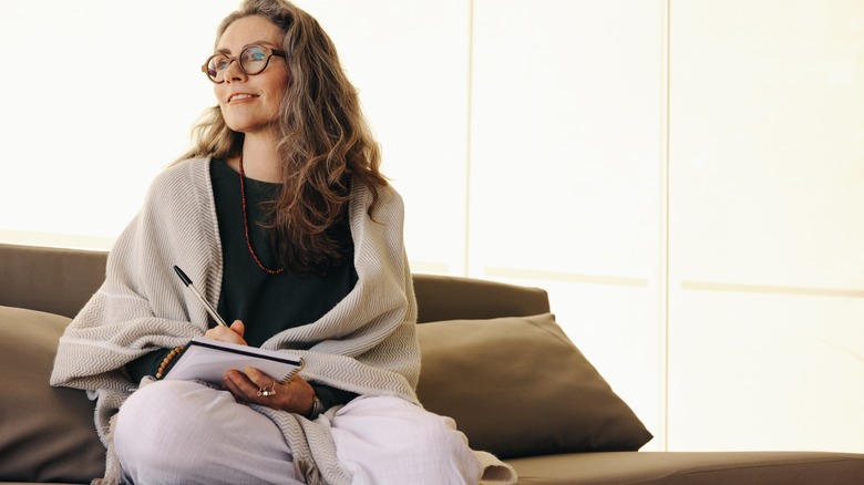 woman sitting on couch writing in journal