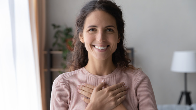 woman smiling with hands against chest