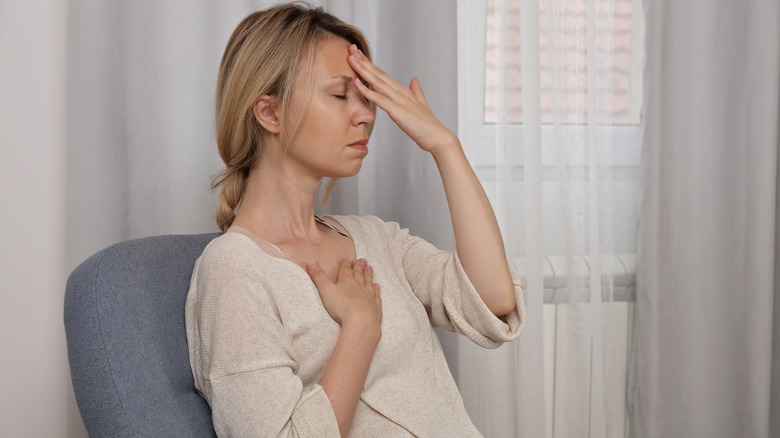 woman with hands on heart and head practicing grounding