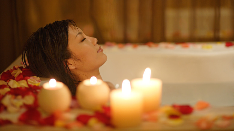 woman taking a bath with candles and rose petals