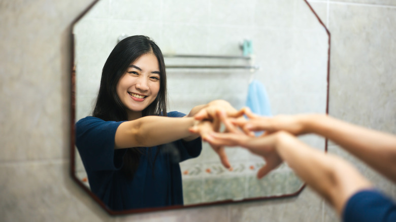 woman hands out toward mirror