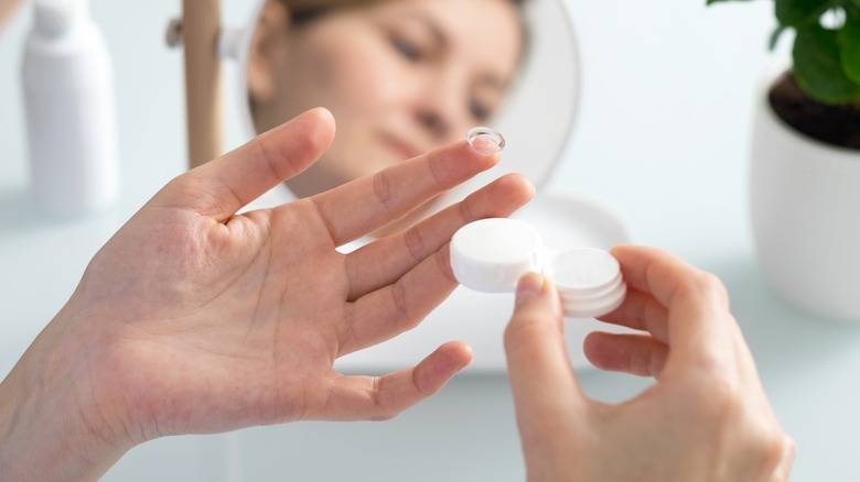 Woman holding contact lenses