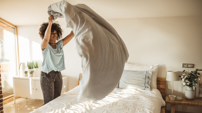 woman making her bed in morning