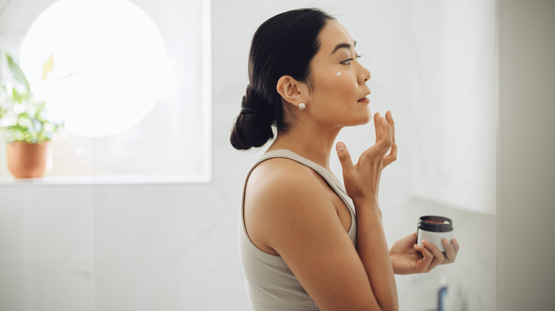 woman applying face cream in the morning