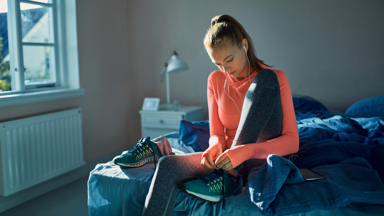 woman putting running shoes on in morning