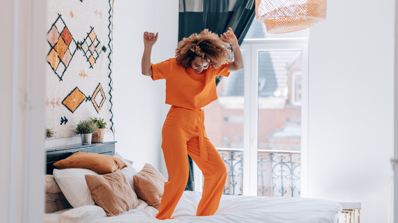 woman in orange pajamas dancing in bedroom