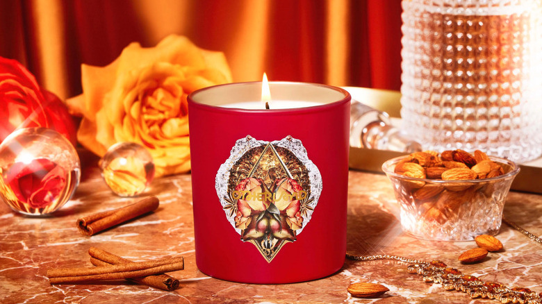 red candle on a marbled table surrounded by cinnamon and almonds