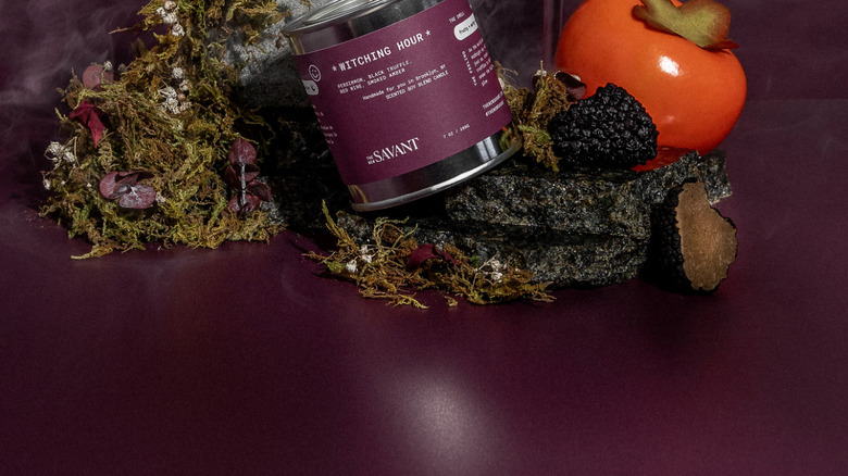 product image of candle in purple tin surrounded by red wine, berries, and greenery