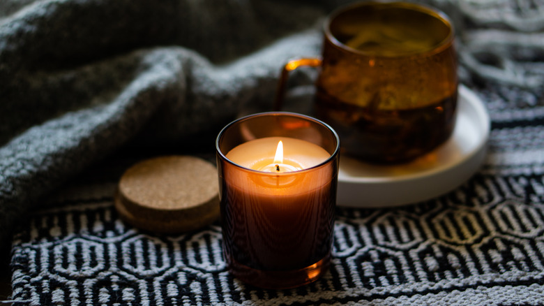 two candles in brown glass jars atop a black and white placemat, fall/winter home decor