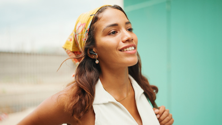 A woman with a bandana smiling while listening to music.