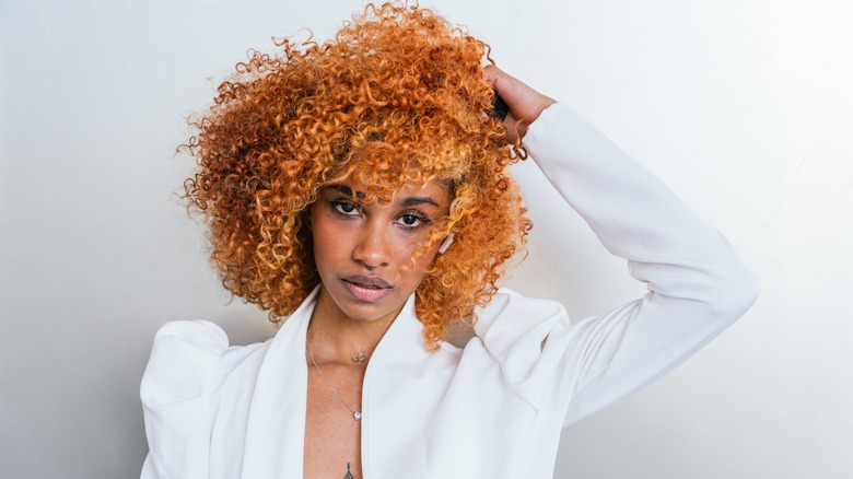 A woman with curly copper red hair posing for the camera.