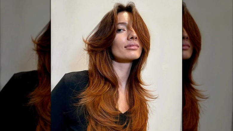 A woman with layered hair posing for a photo.