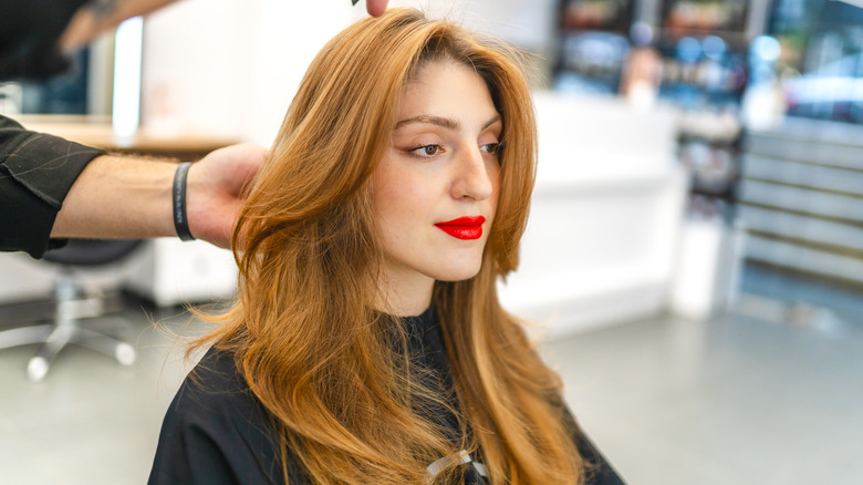 A woman getting her hair styled at a salon.