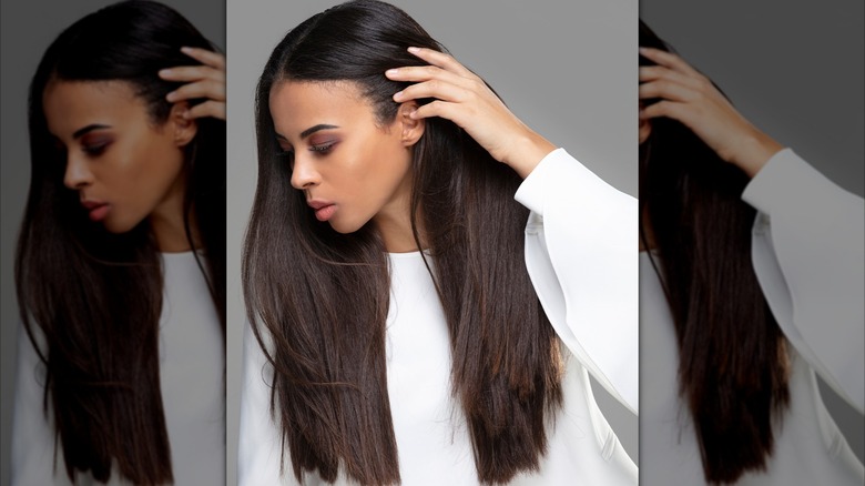 A woman touching her long hair.