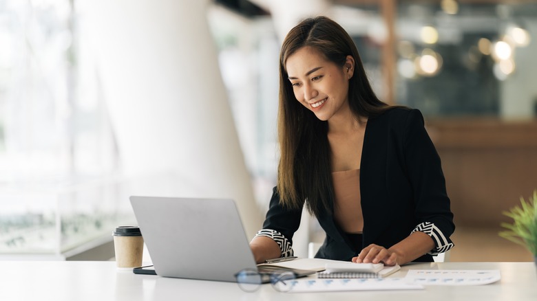 Woman smiling, working on laptop 