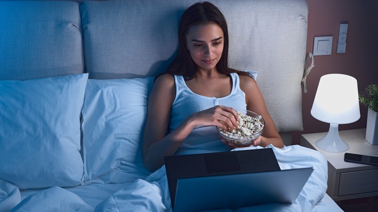 woman eating popcorn in bed