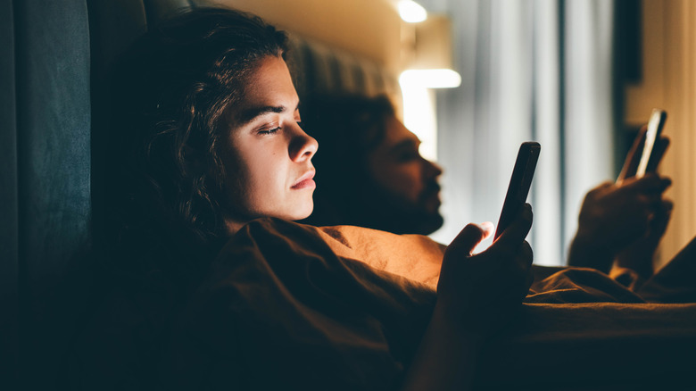 Couple on phones in bed