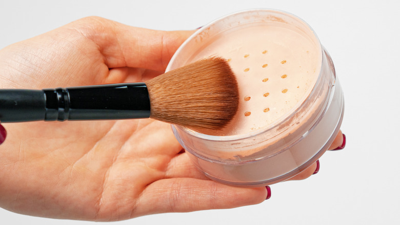 A hand using loose powder