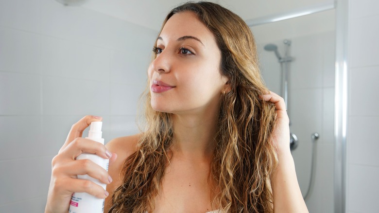 A woman applying spray to her hair