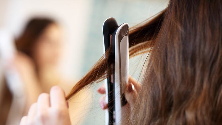 A woman straightening her hair