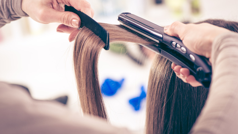 A woman straightening her hair while combing