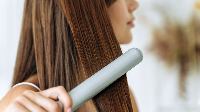 A woman straightening her hair