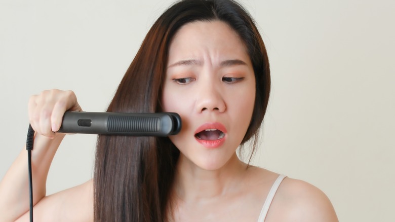 A distressed woman straightening her hair