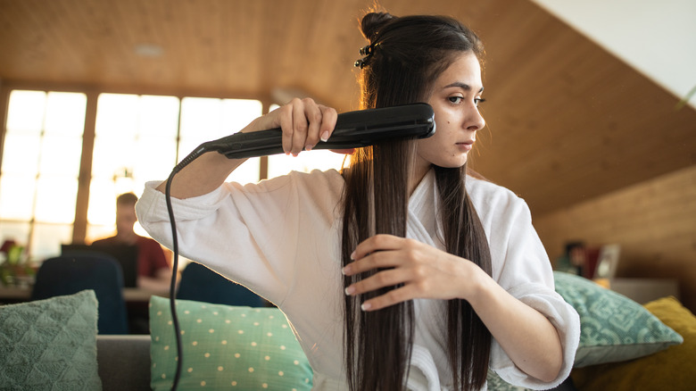 A woman sitting and straightening her hair