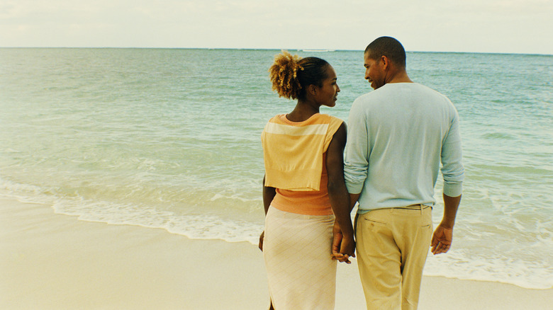 Black couple walking along beach