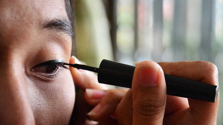 woman using black eyeliner