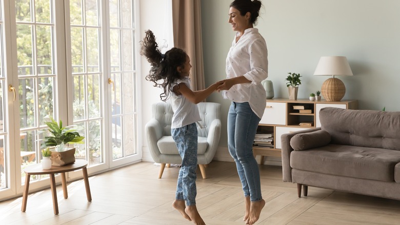 mother and daughter jumping in living room