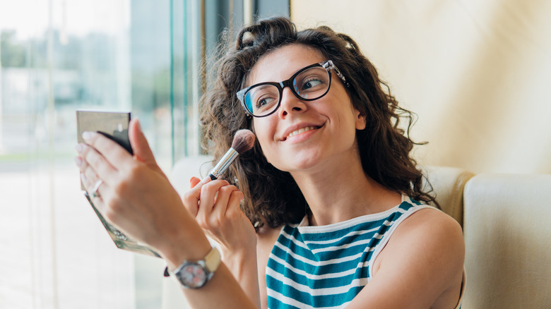 A woman applying blush