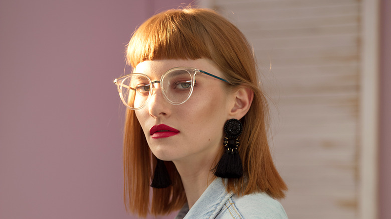 A woman wearing glasses with a red lip