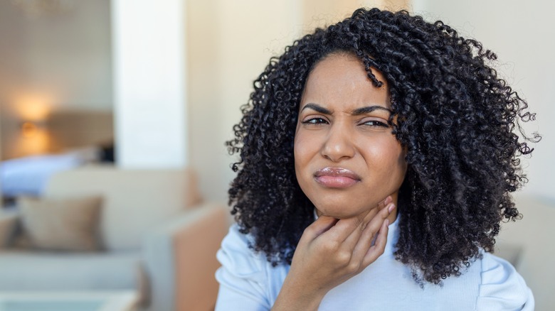 Woman in pain pressing throat 