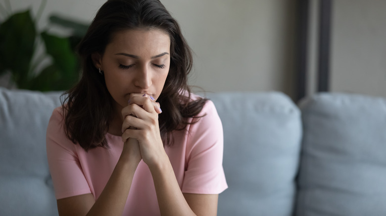 Woman closing eyes, clenching hands