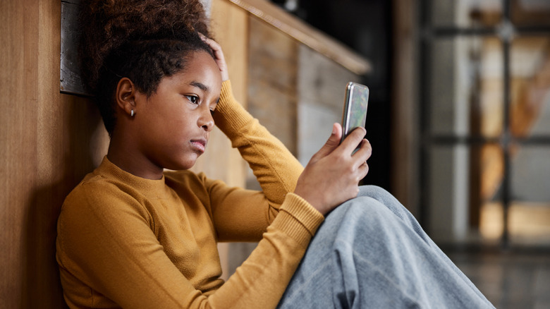 Woman holding phone, appearing down