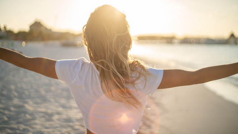 Woman at beach holding arms out