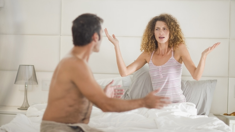 woman shrugging in bed man upset 