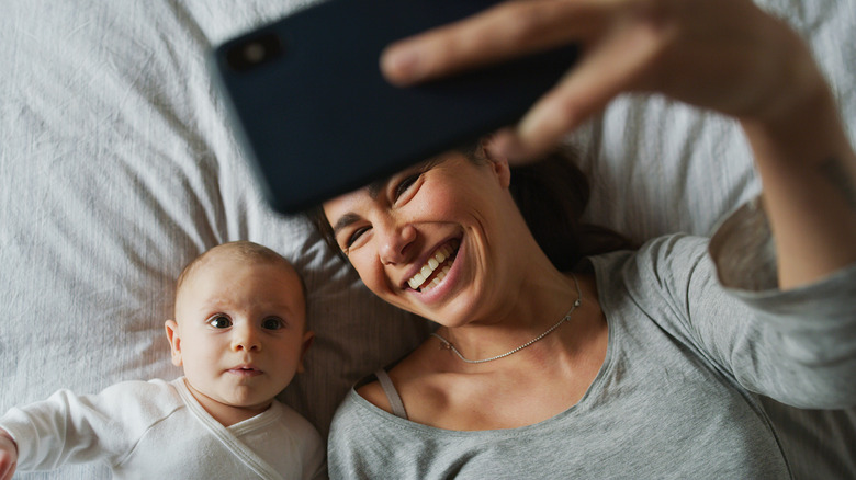 Woman taking selfie with newborn