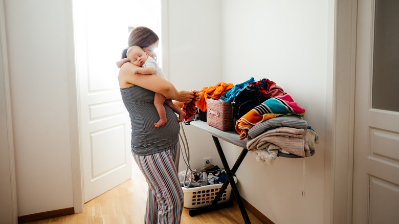 Mom folding laundry holding baby