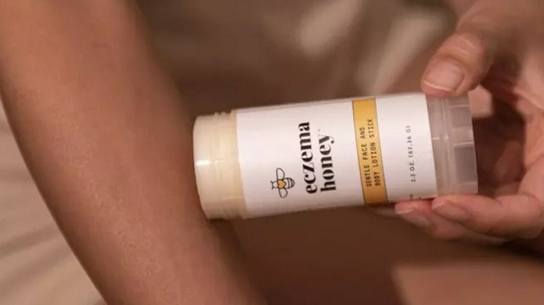 person using eczema balm stick