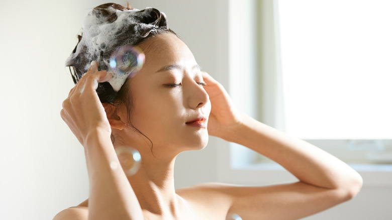 Person shampooing hair with bubbles