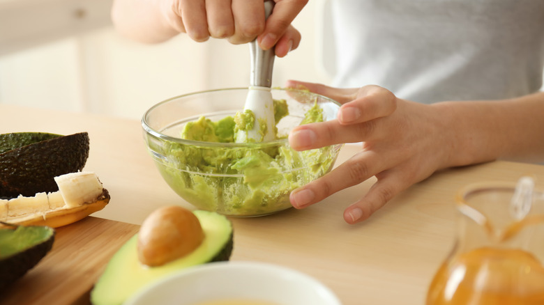 Woman crushing an avocado in a bowl to do a facial mask