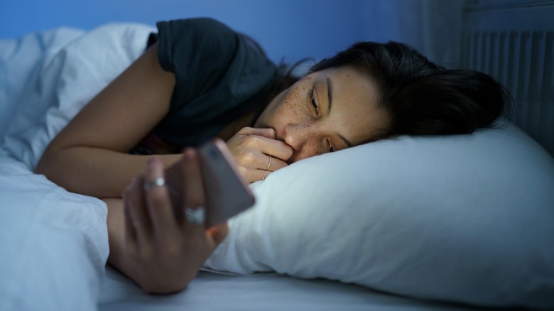 Woman staring at phone in bed 