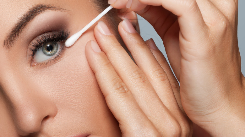 Woman cleaning up eyeshadow with cotton bud 