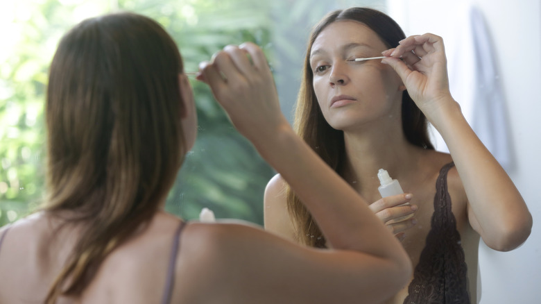 A woman using serum on her lashes