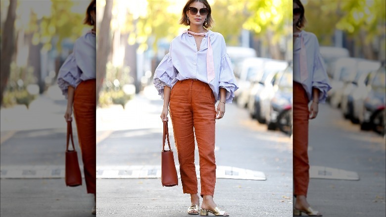 Person in orange pants and gold sandals