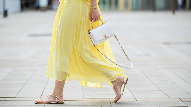 Person in yellow skirt and gold sandals