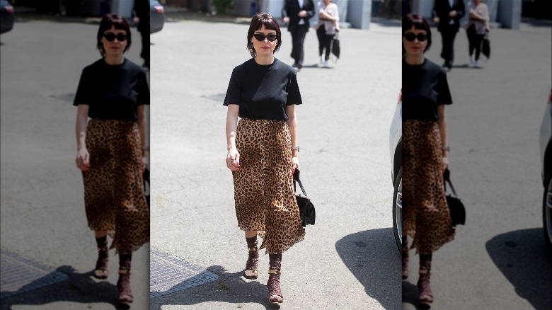 Person in leopard skirt and gold sandals