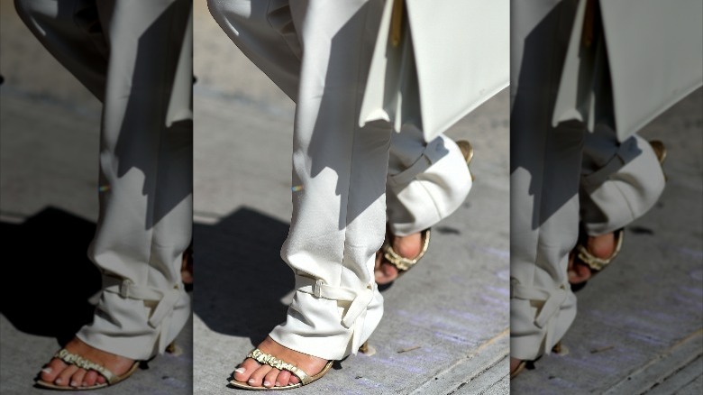 Person in trousers and gold sandals